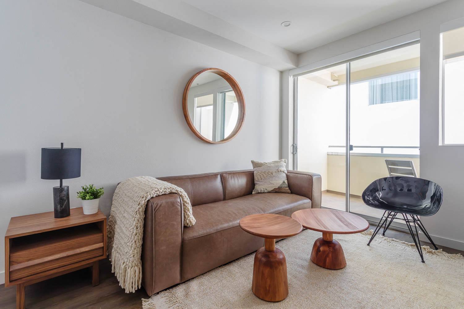 a living room with a brown couch and a round mirror on the wall